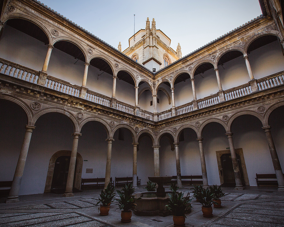 Vista desde abajo de uno de los patios del Hospital Real donde se ven los arcos del pasillo superior y la torre